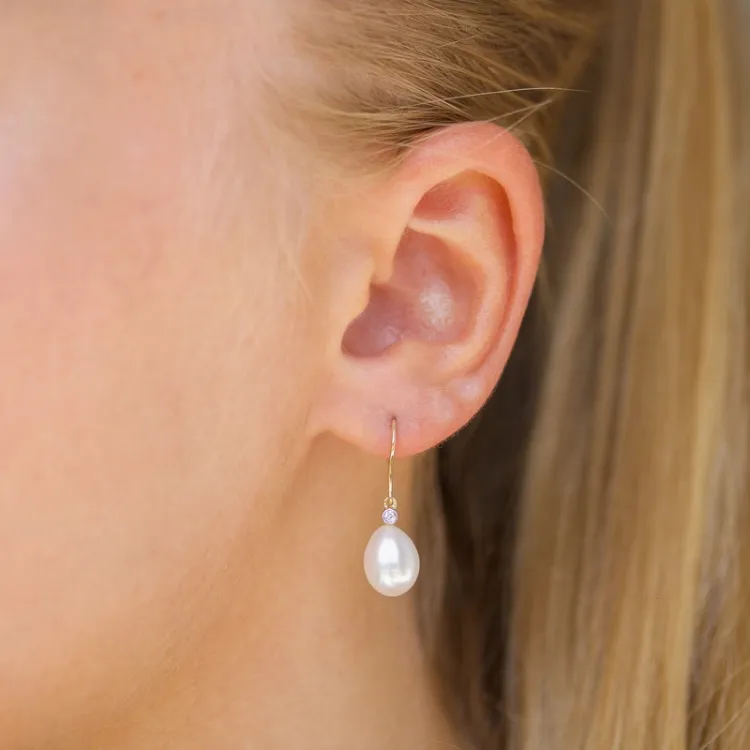 Ovale 7 - 8 mm aaa-graded ferskvandsperle diamantøreringe i 14 karat guld med diamanter 